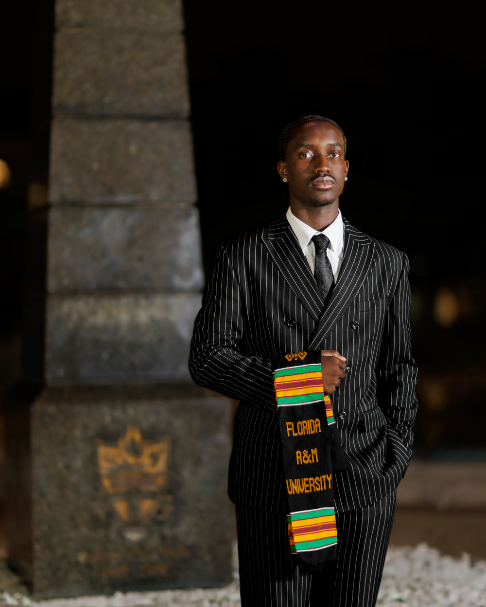 Professional portrait series showing a person in a pinstriped suit with a colorful African-inspired folder against a dark wall.
