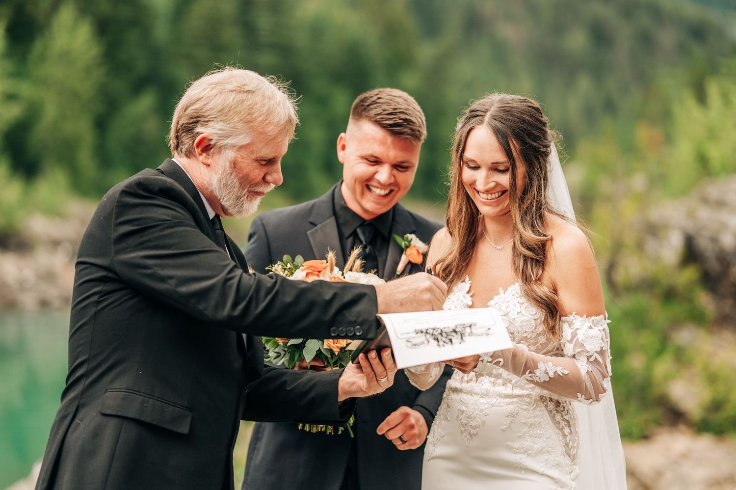 A joyful celebration unfolds at an outdoor wedding ceremony with a scenic mountain and forest backdrop.