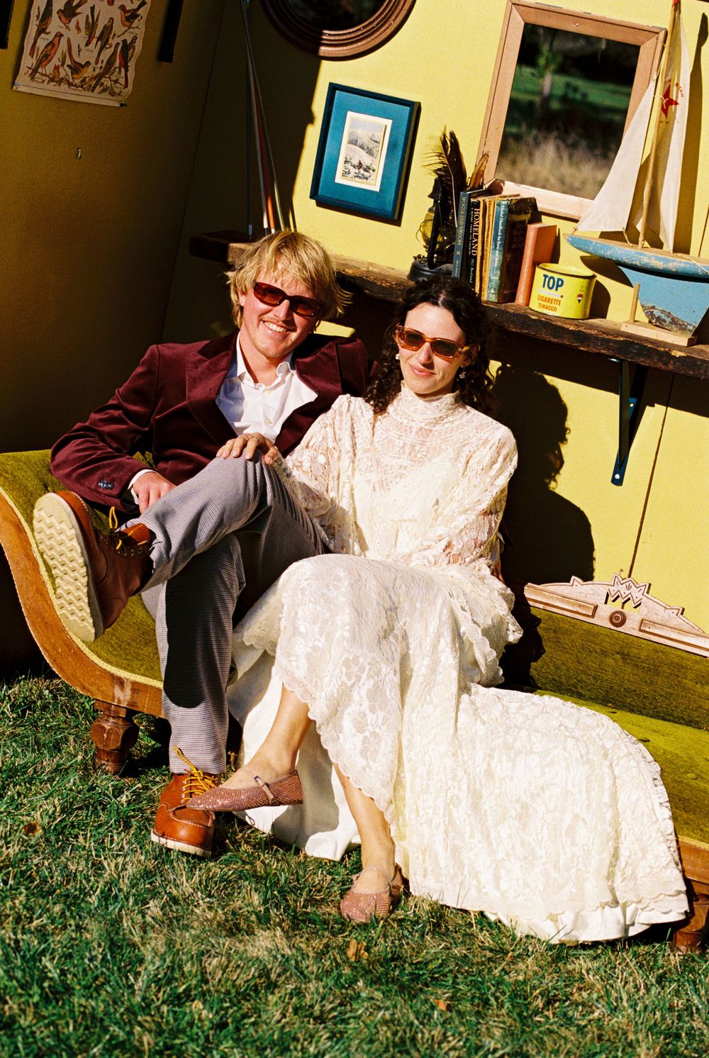 The couple smiles after getting married while wearing sunglasses and posed in front of their handmade cabin style Photo Booth in Kennebunk.