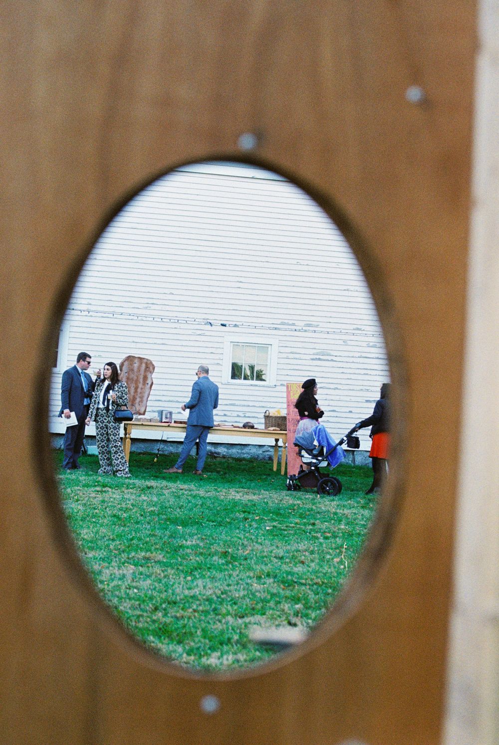 People getting appetizers after the wedding ceremony and being seen through the vintage photo frames of a handmade Photo Booth in Maine.