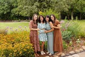Group photo of people wearing coordinated outfits in a blooming garden with yellow flowers.