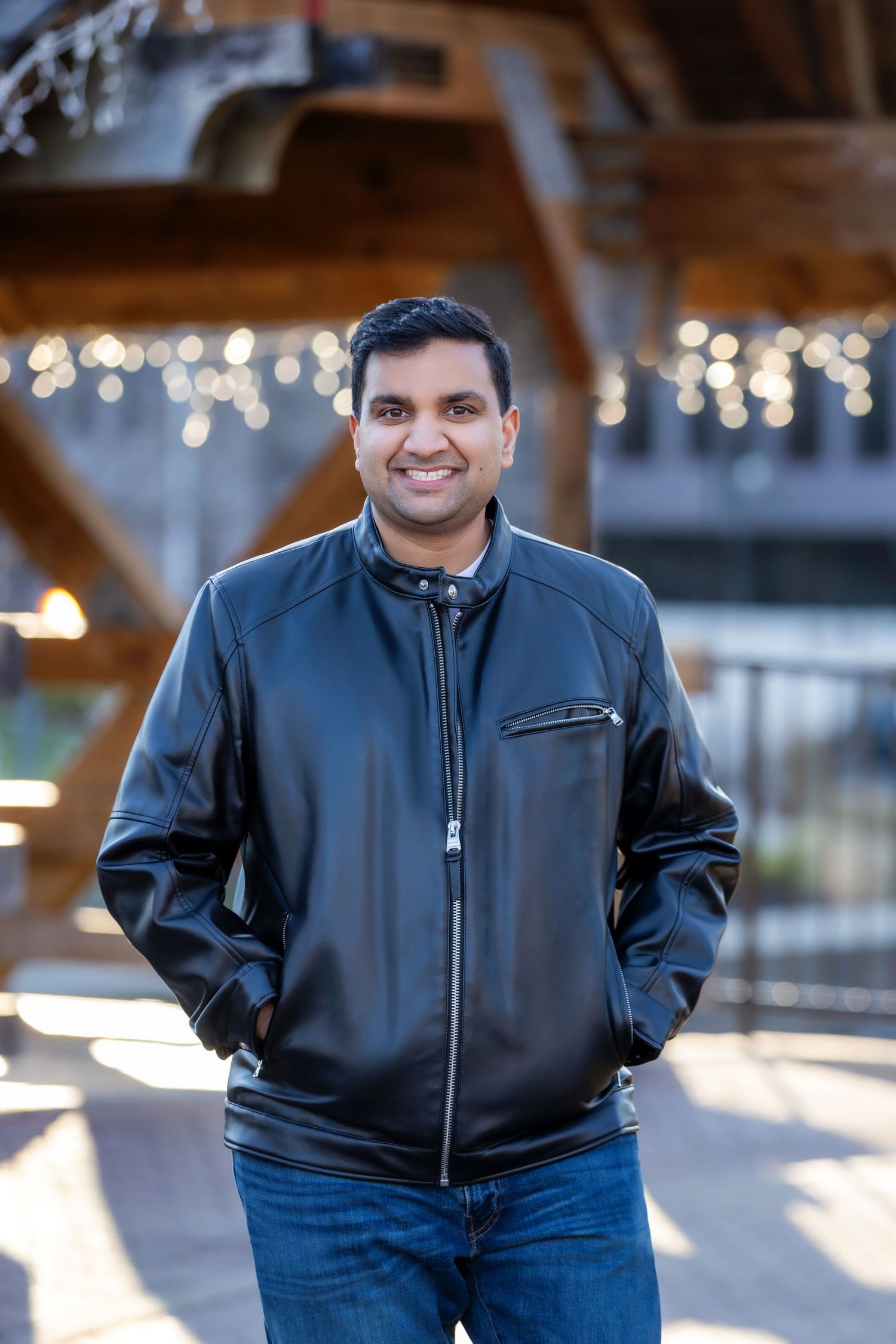 A casual fashion photo series showing a black leather jacket paired with blue jeans in an indoor setting with bokeh lights.