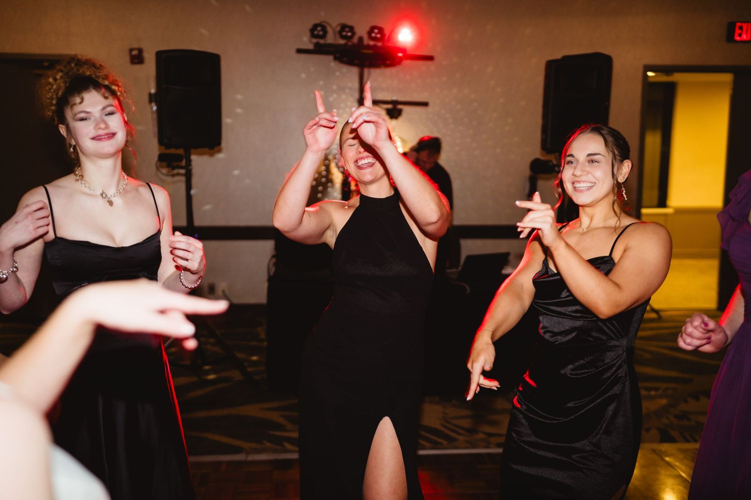 People dancing and having fun at a dimly lit party with red lighting effects in the background.