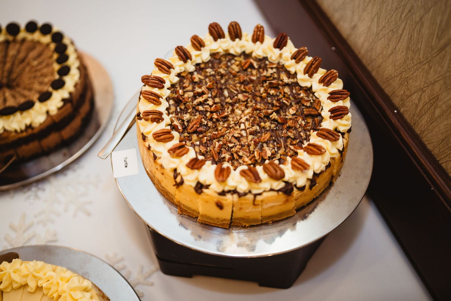 Chocolate pecan pie topped with whipped cream and arranged pecans in a decorative circular pattern on a white plate.