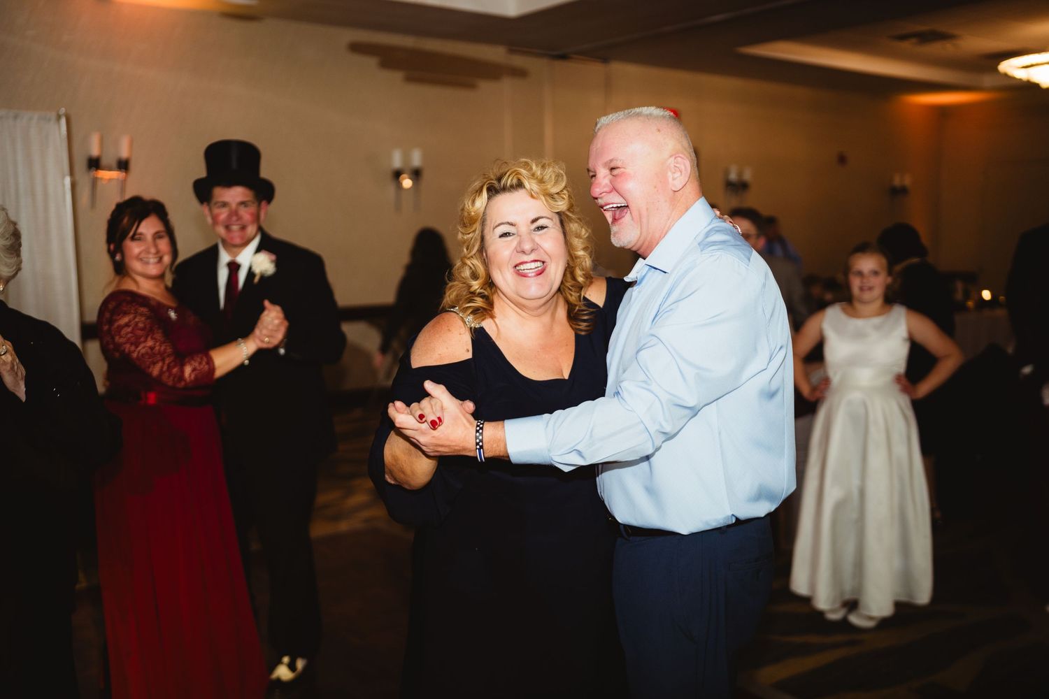 Couples dancing together at an evening wedding reception with warm lighting.