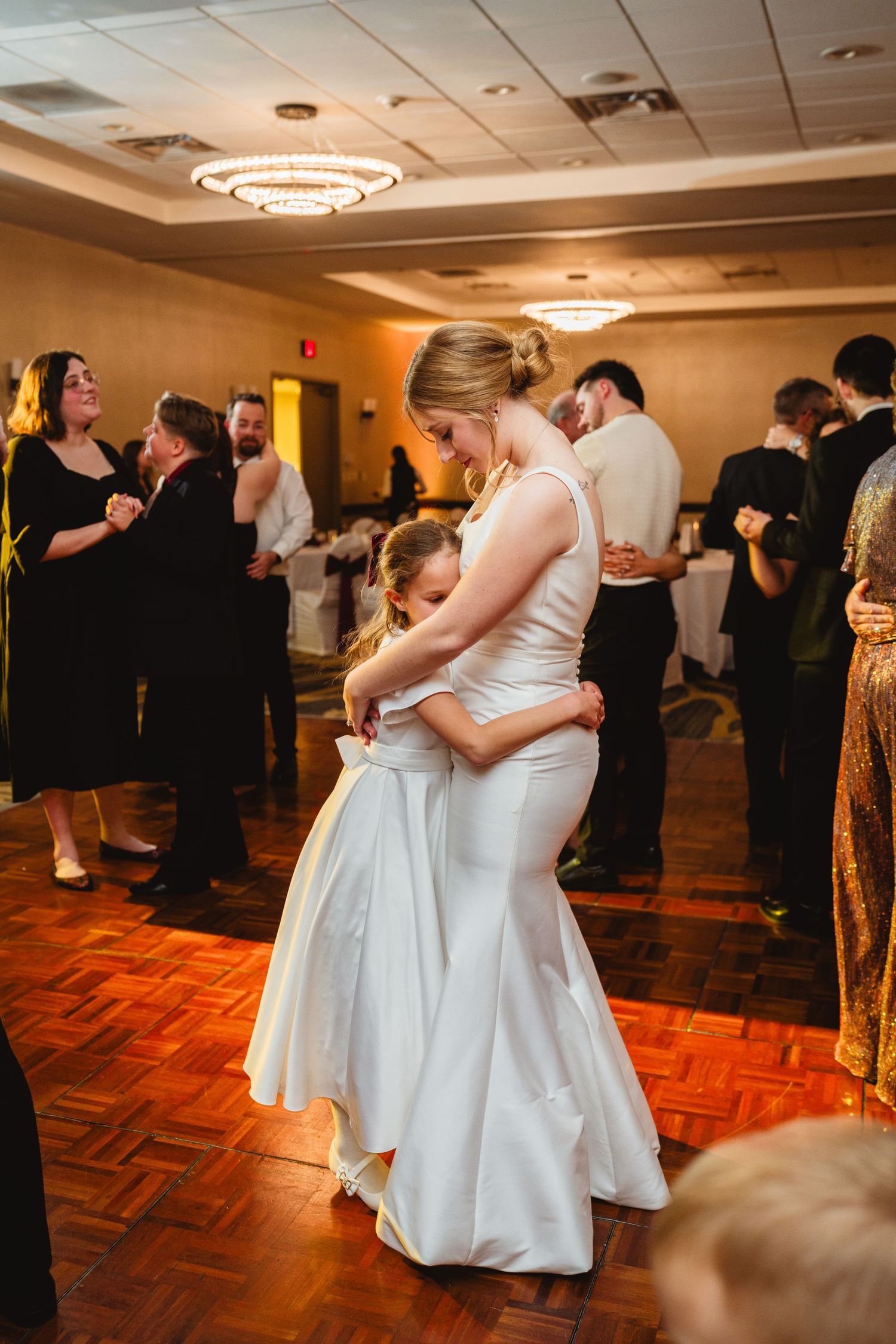 Couples slow dance together on a parquet dance floor at an elegant indoor wedding reception.