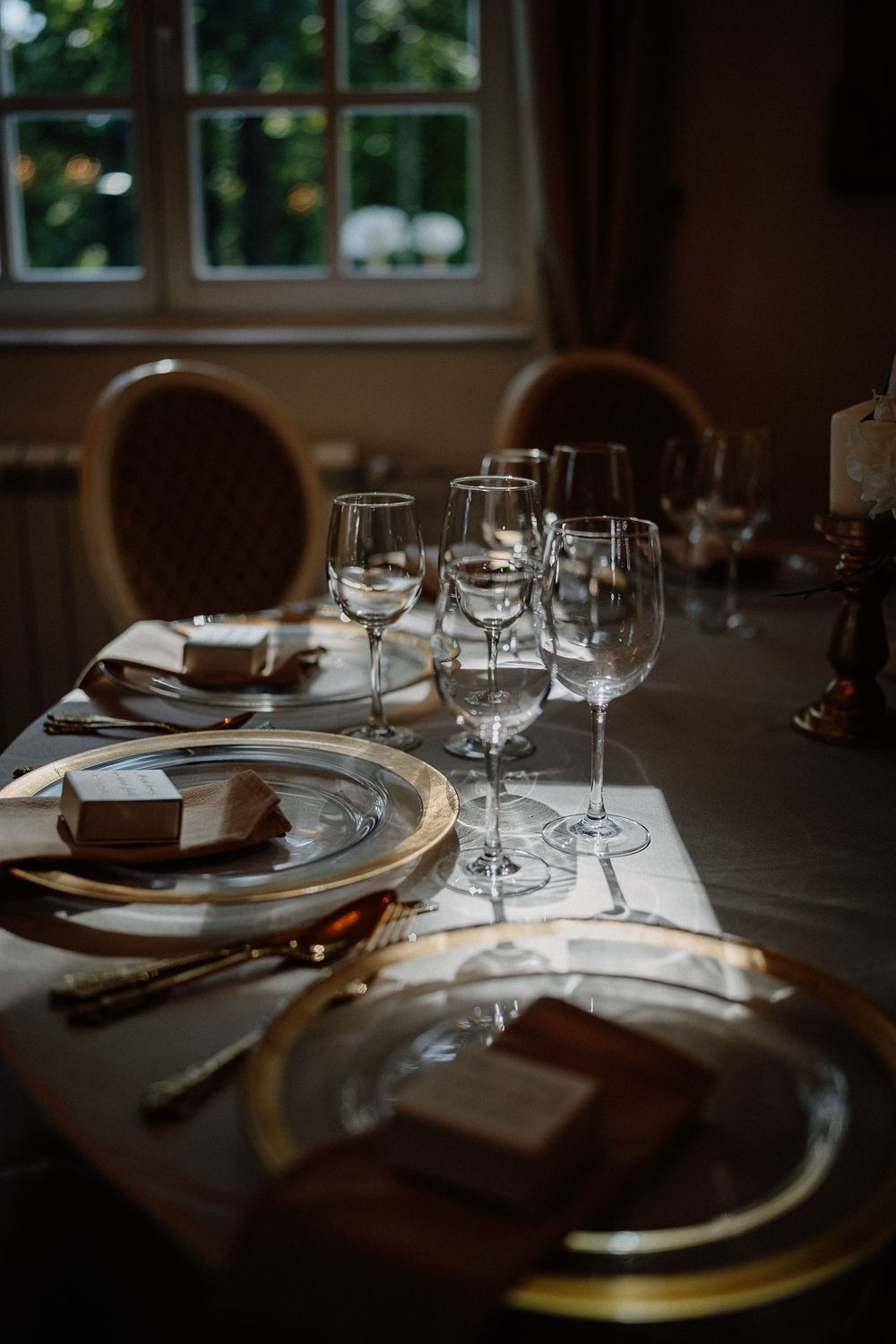 Elegant table settings with wine glasses and plates arranged in a dimly lit restaurant interior.