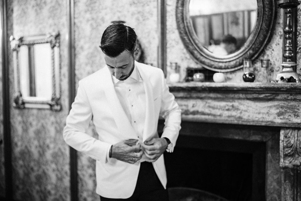 A black and white photo shows a person in a white chef's coat working in an elegant dining room setting.