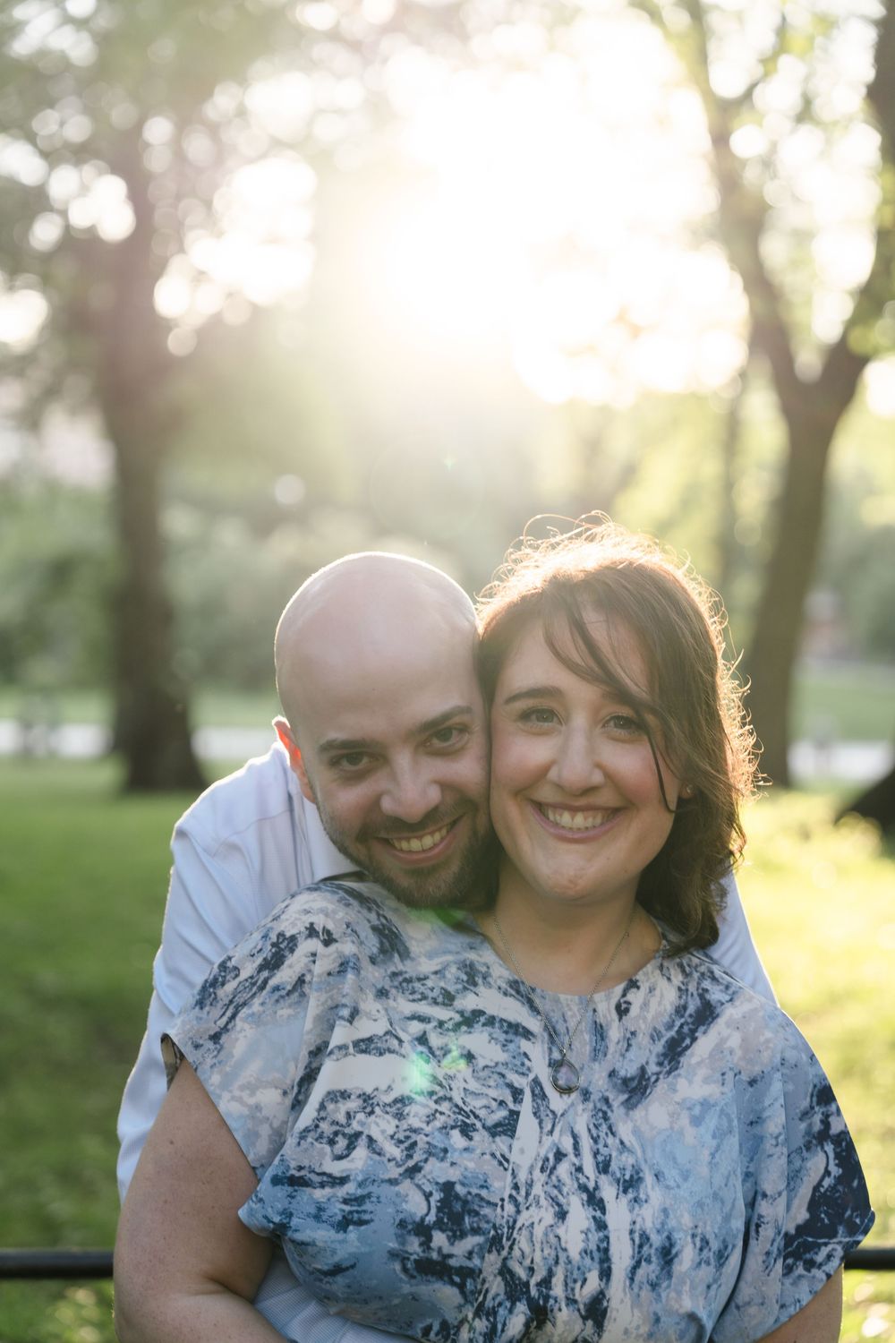 A couple shares joyful moments together in a sunlit park during a spring photo session.
