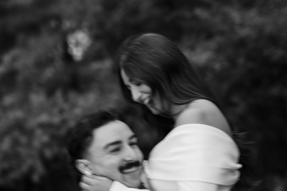 A black and white photo of a couple in an intimate embrace outdoors.