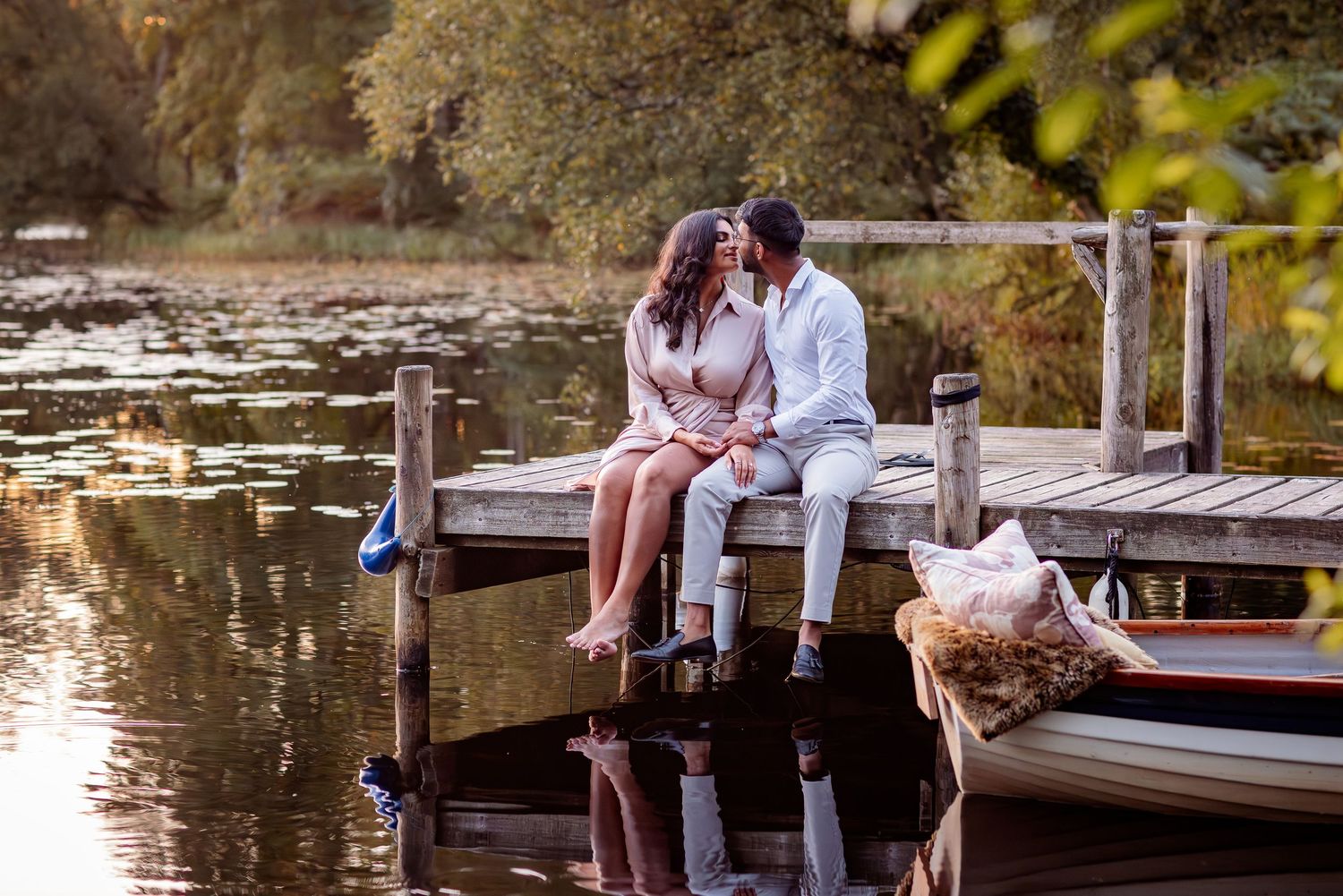 A couple sits on the wooden dock at Giplin Hotel and Lake House at sunset and embrace.