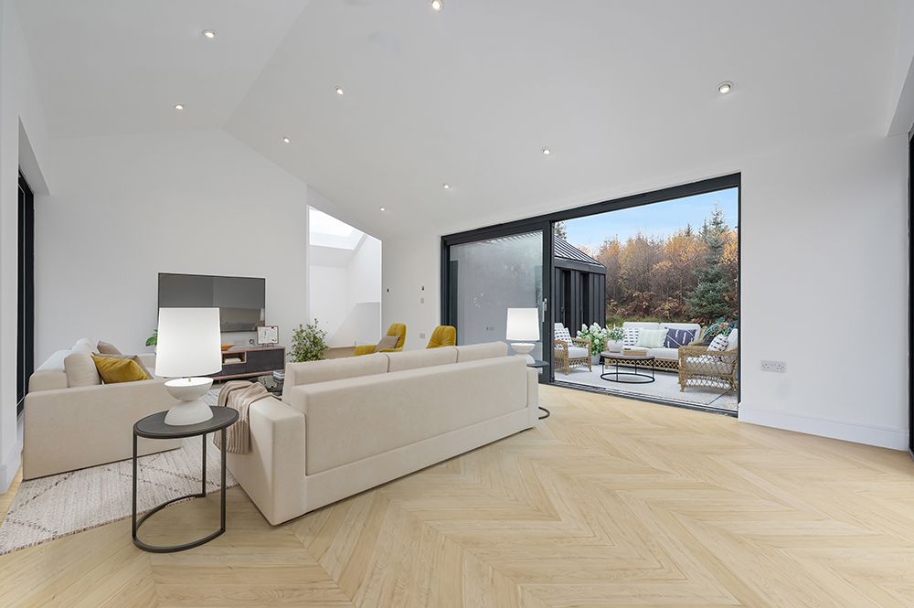 Modern living space with pine herringbone floors and large windows letting in natural light.