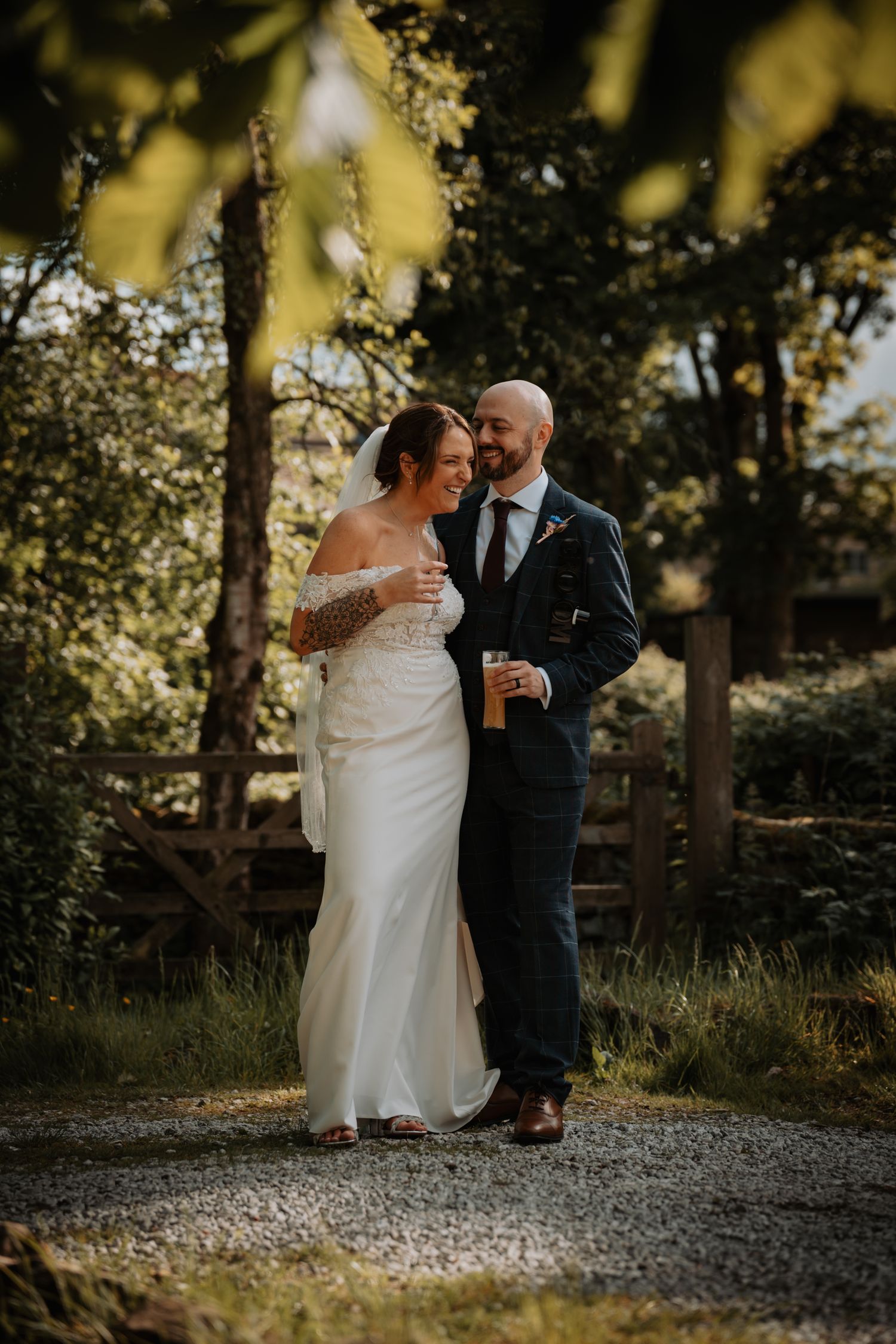 A couple shares an intimate moment on their wedding day in a sunlit wooded setting.