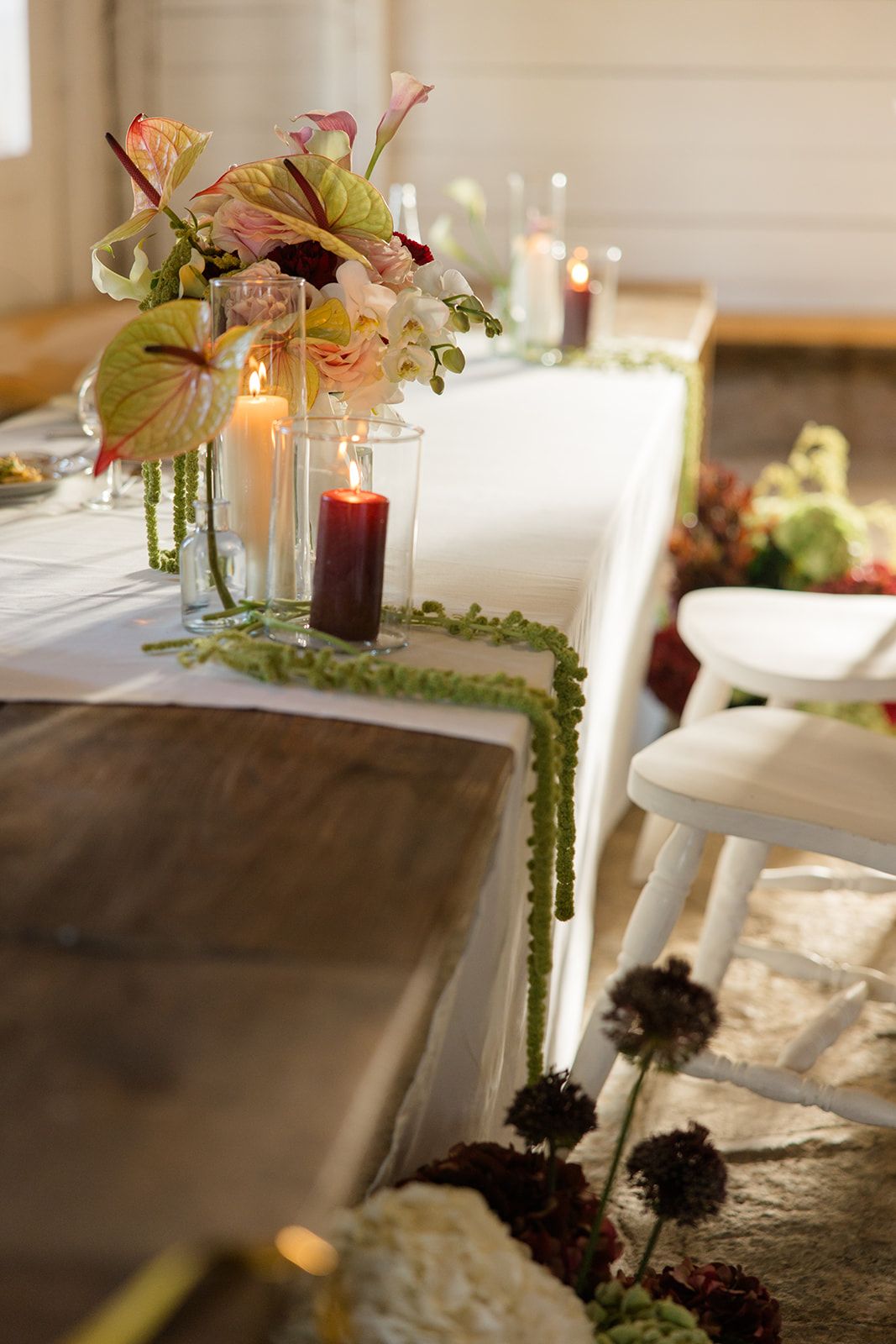 Elegant table setting with glowing candles and delicate floral arrangements on white linens creating a romantic atmosphere.