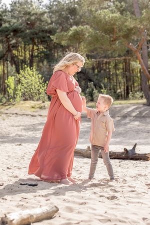 aanstaande mam samen met zoontje kijkend naar haar zwangere buik, waarbij zoontje aanwijst waar de baby is.