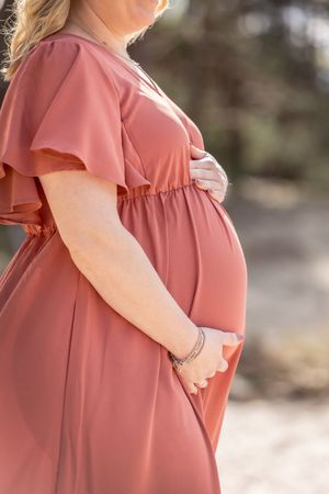 buikfoto van een zwangere vrouw in rode jurk