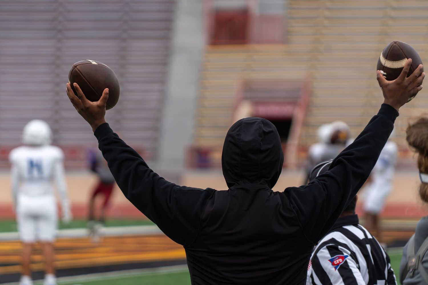 Football referee signals touchdown with both arms raised overhead during a game.