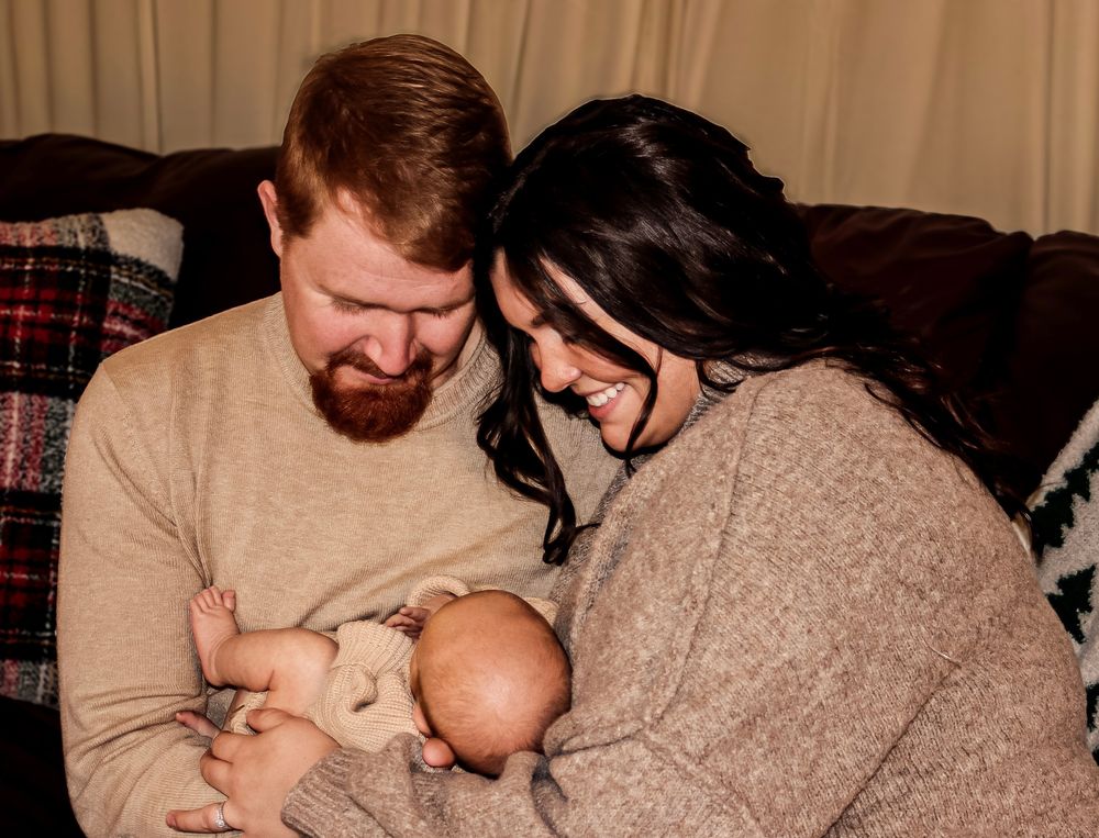 Intimate family portrait with parents, holding baby, natural connection, and candid lifestyle photography in Michigan