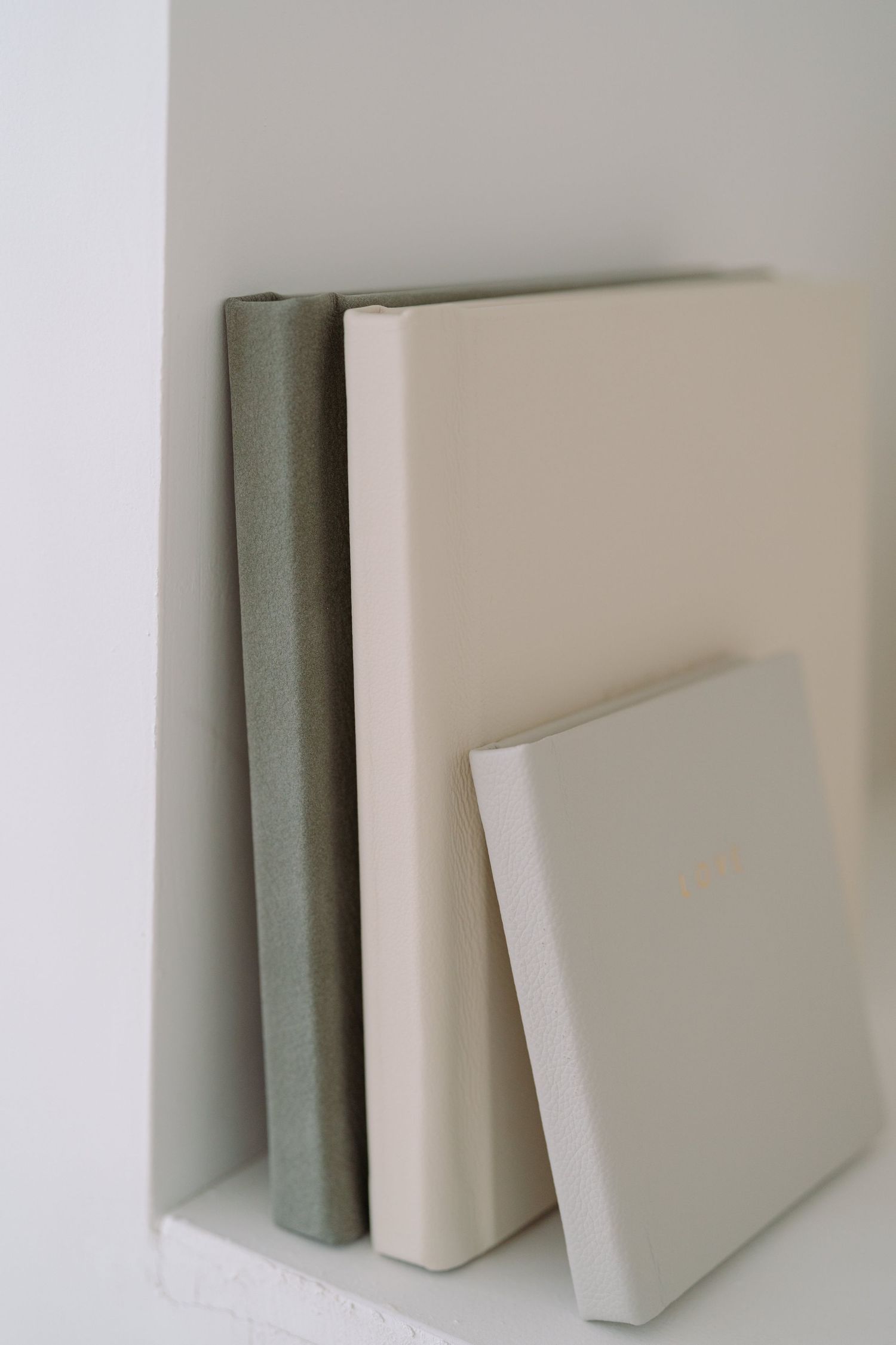 Three minimalist white and gray books arranged against a light background showing different thicknesses and angles.