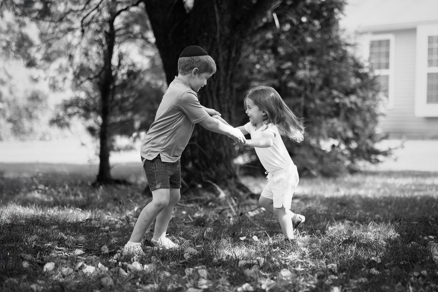 monochromatic photo of siblings playing together in the shade