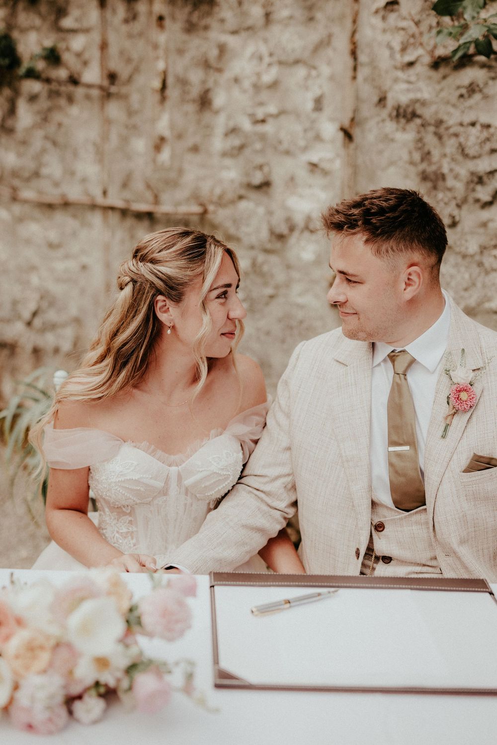 A romantic wedding couple shares intimate moments in a series of candid photos against a stone wall background.