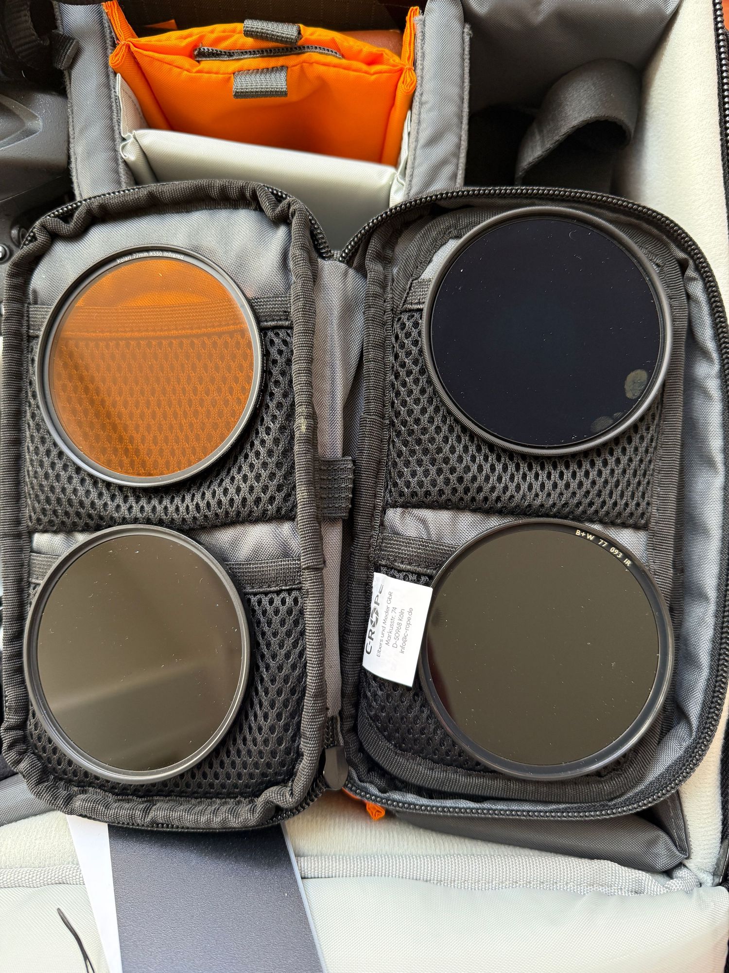 Camera filter case with four circular filters including orange and ND filters.