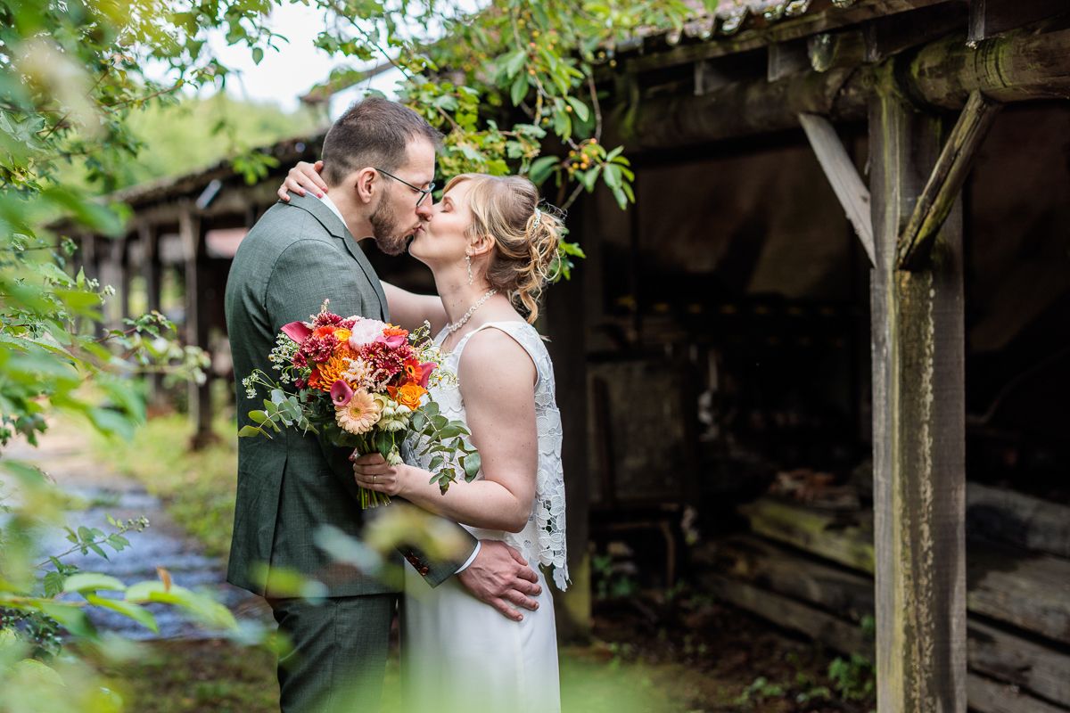 A tender embrace between newlyweds on a manicured lawn with brick wall background.