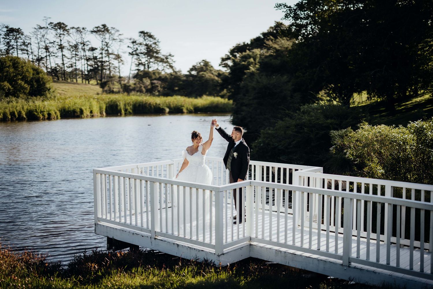 A couple in traditional Indian wedding attire walks through a forest path at sunset.