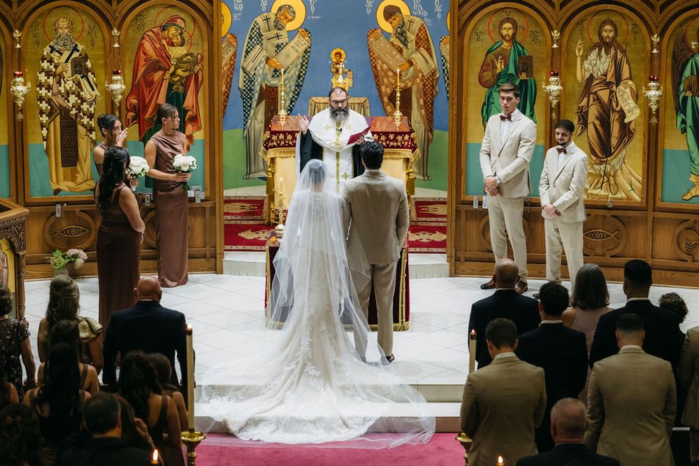 Orthodox wedding ceremony in ornate church with bride in white gown and veil standing at altar with groom and priest in Chicago