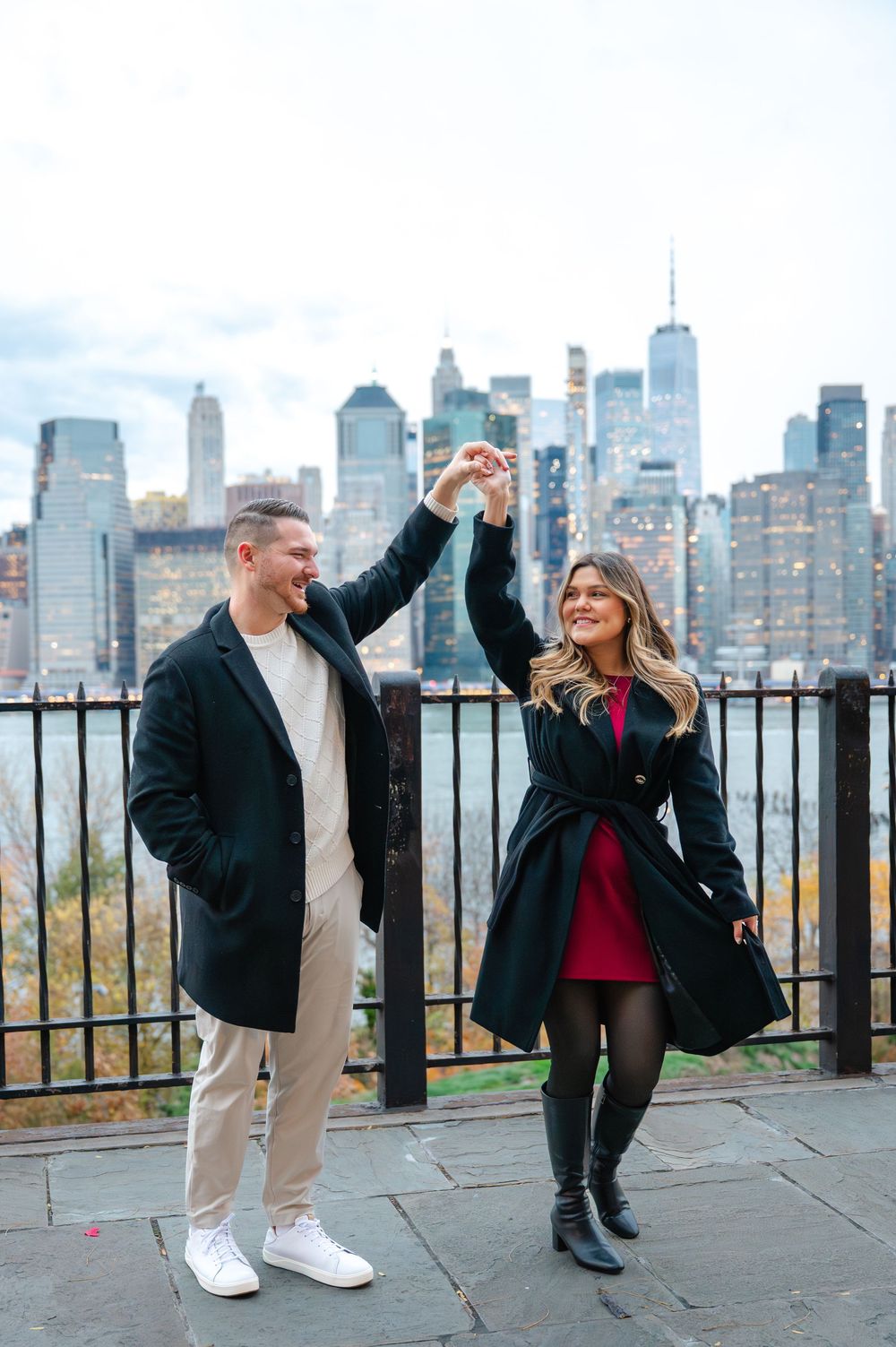 Couple celebrates engagement dancing on Brooklyn Heights Promenade with NYC skyline.