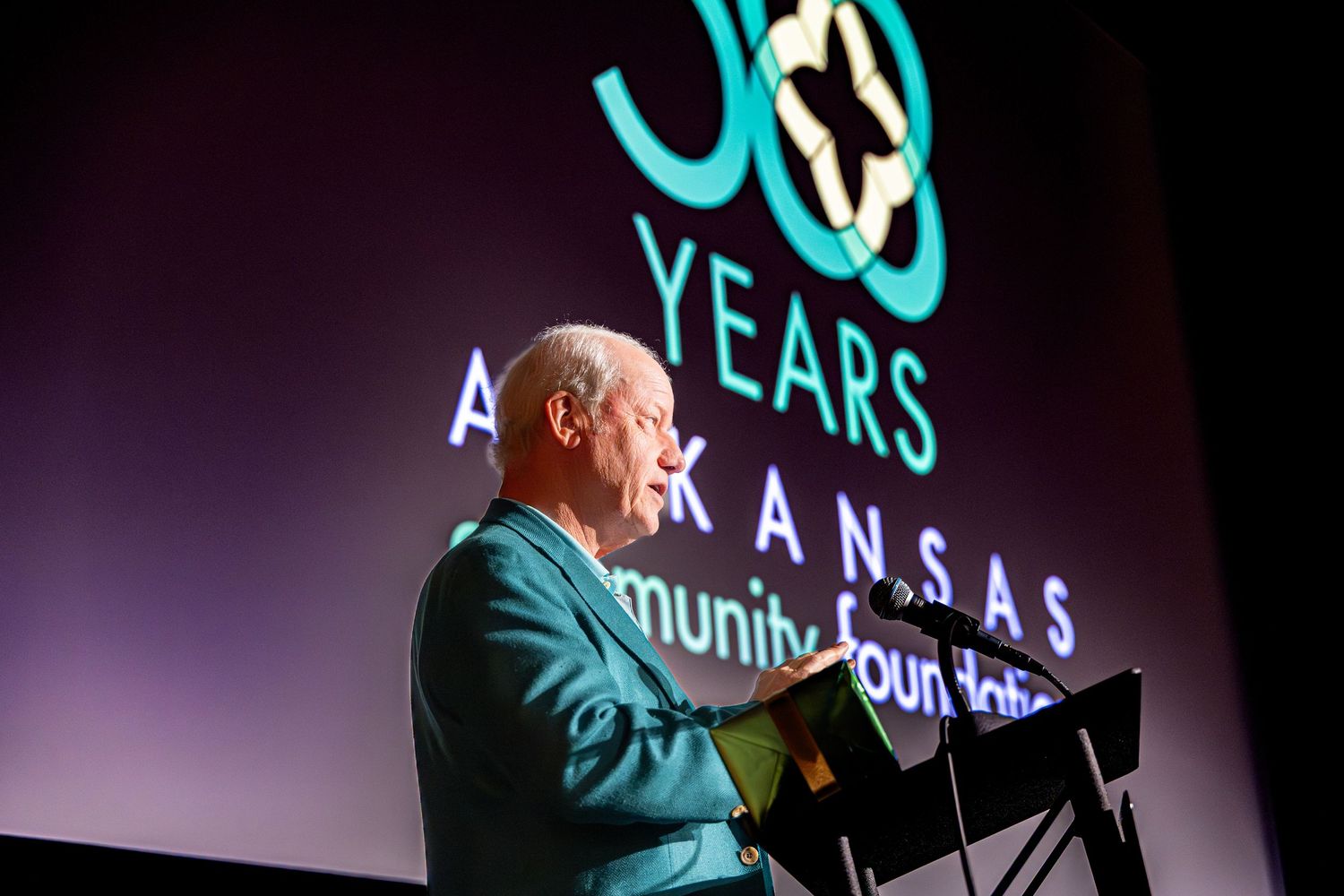 Man in teal suit speaks at podium during Arkansas Community Foundation 30th anniversary celebration event.