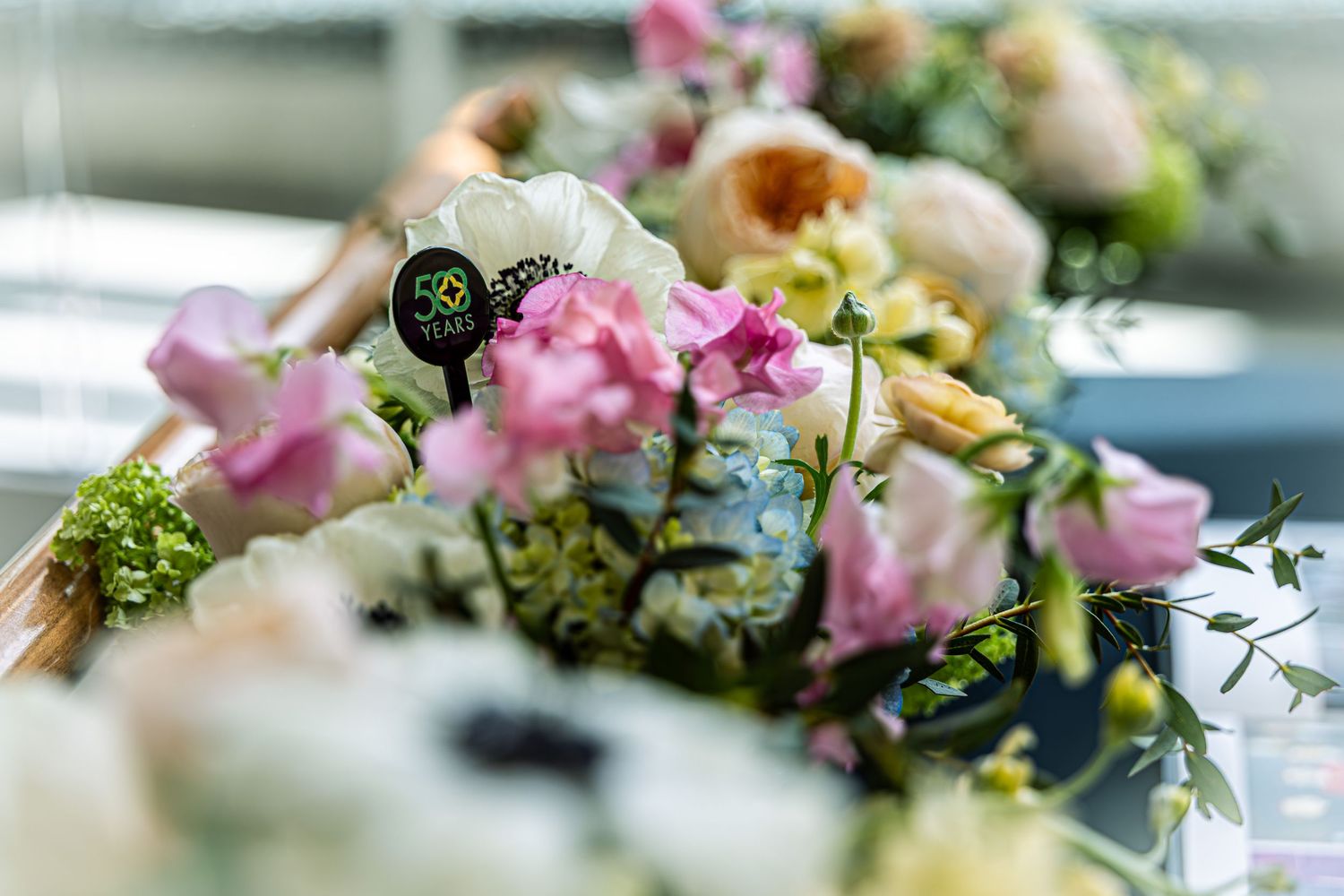 Close-up of elegant pink and white floral arrangement with a 50 years anniversary pick at a celebration event.