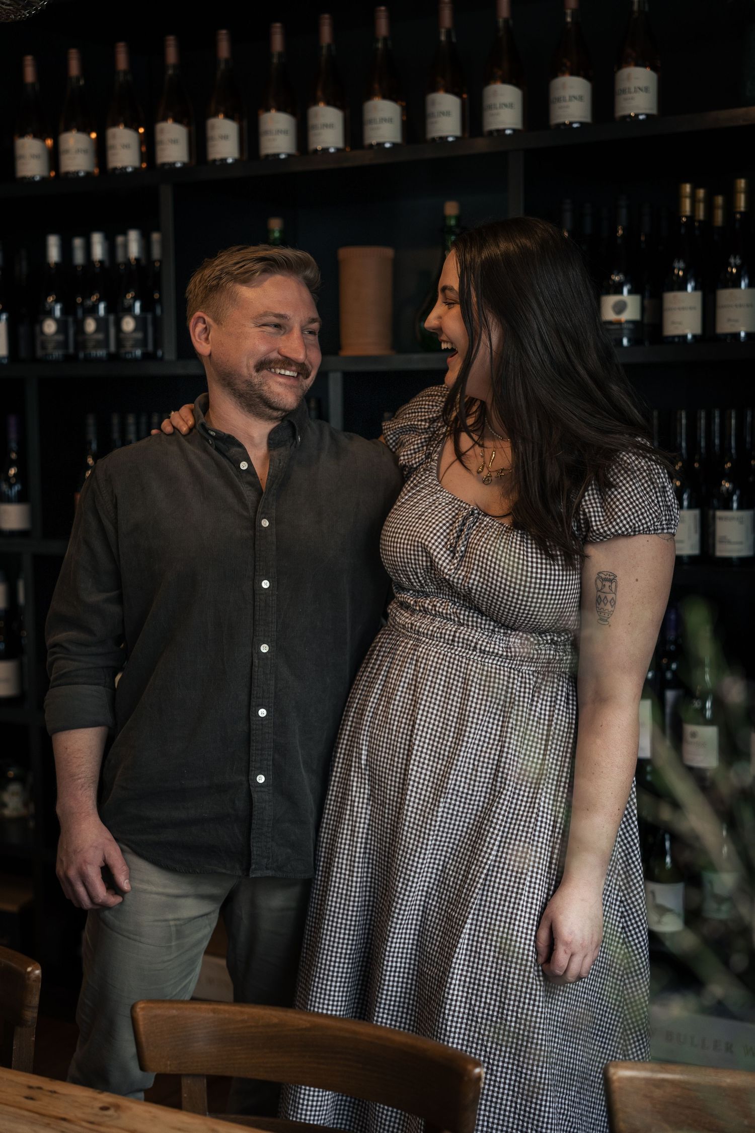 A smiling couple stands together in a wine bar surrounded by shelves of wine bottles.

Adeline Trentham