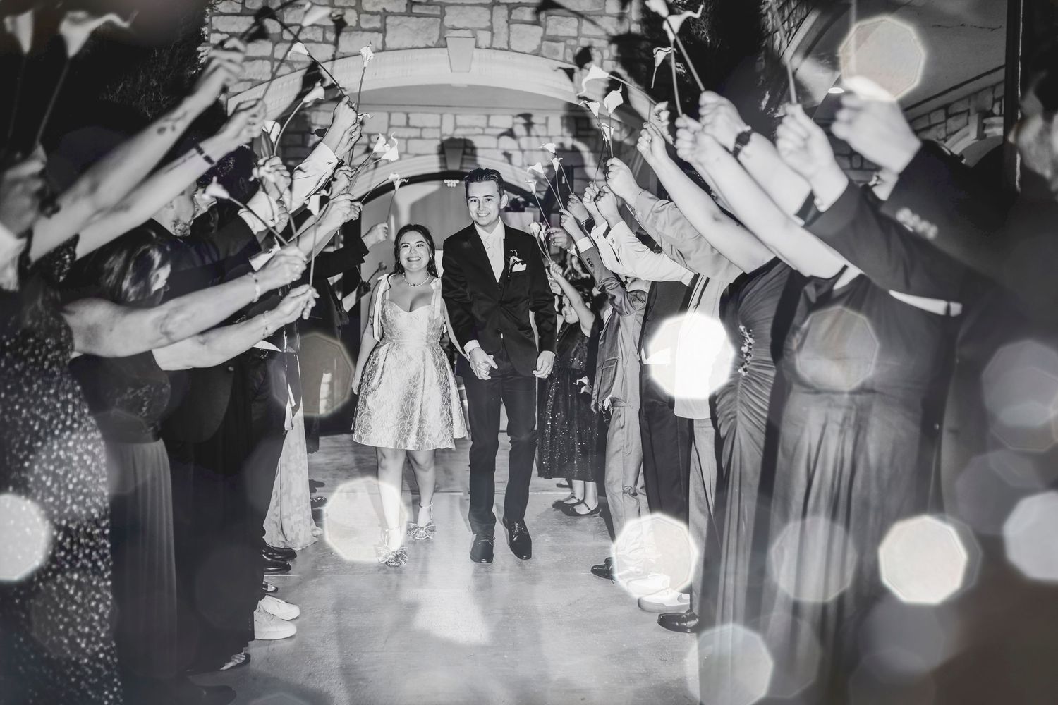 a bride and groom hold hands as they walk through their send off from their dallas wedding