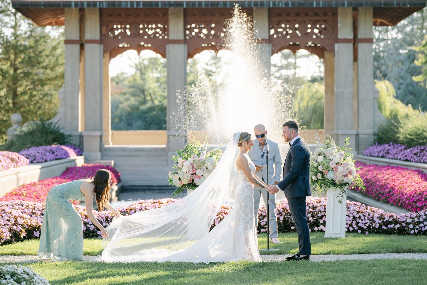 Armour House Wedding - Bride and groom exchange vows outdoors at elegant garden wedding ceremony with lush floral arrangements.