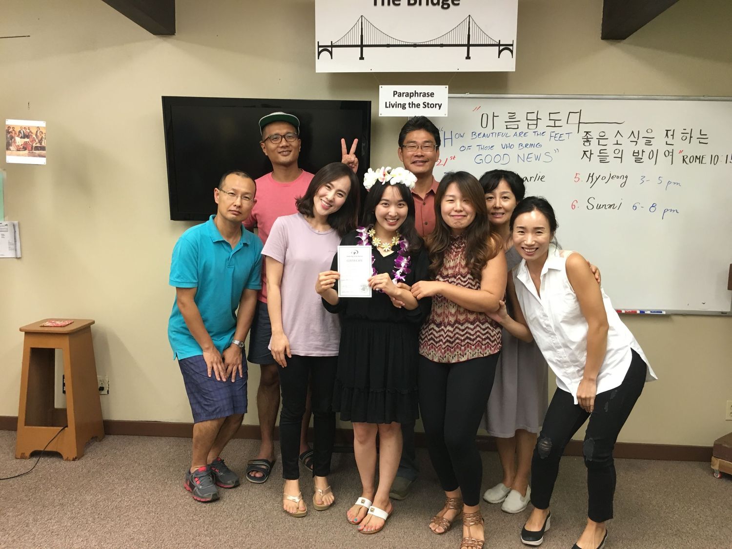 Group of people posing together indoors near a whiteboard with Korean text and English writing at The Bridge.
