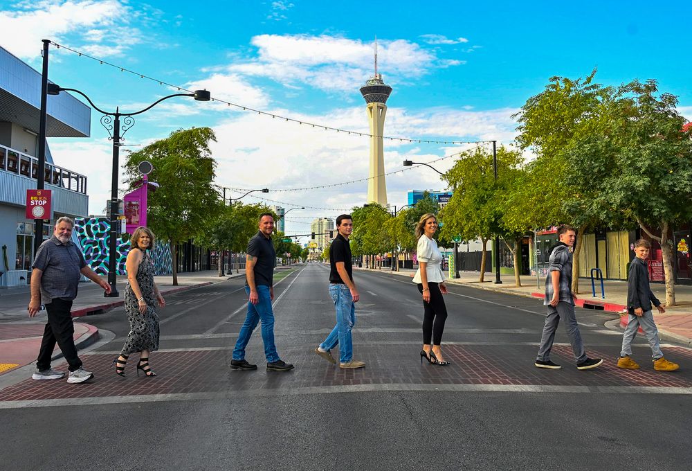 Group of people crossing street Abbey Road style with Las Vegas Stratosphere Tower.