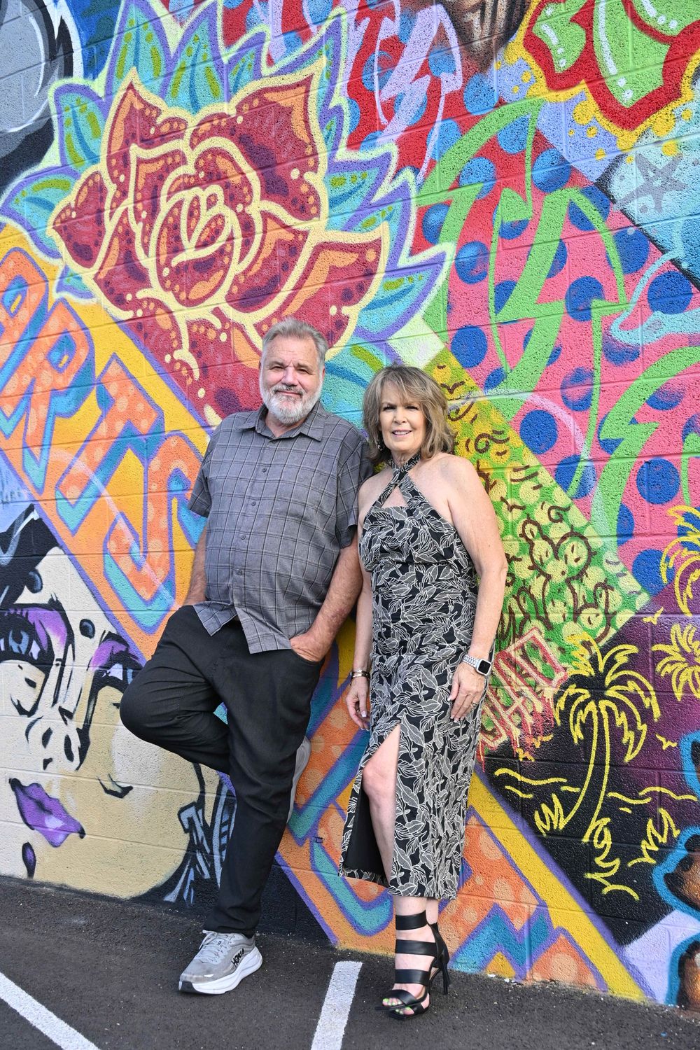 Couple posing in front of colorful graffiti mural wall with vibrant street art.