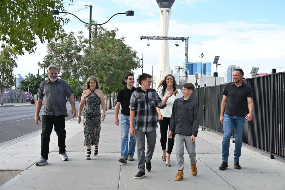Group of seven people walking on a Las Vegas sidewalk with the Stratosphere Tower visible in the background.