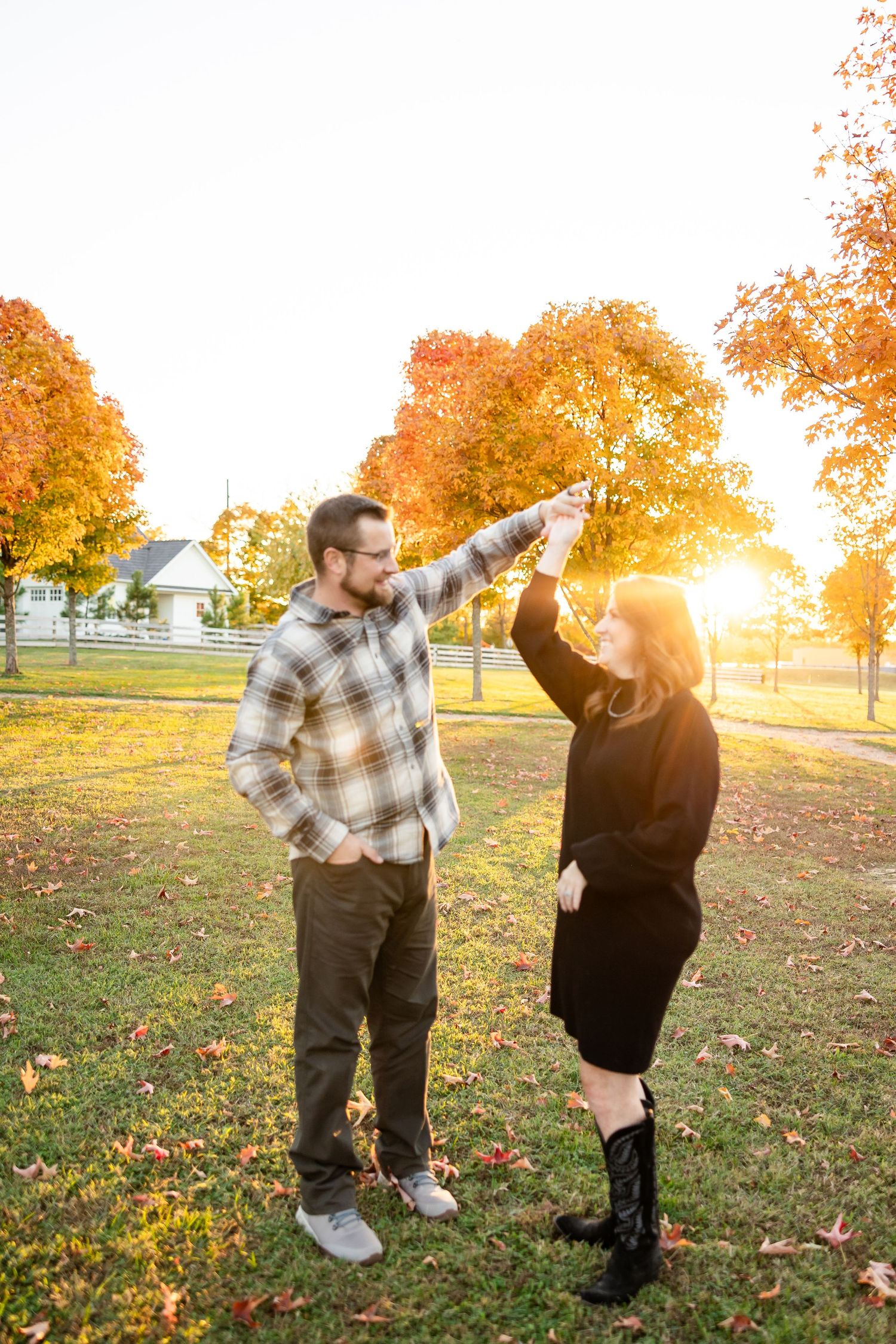 Two people share a joyful high-five moment in a park during autumn sunset with golden foliage in the background.