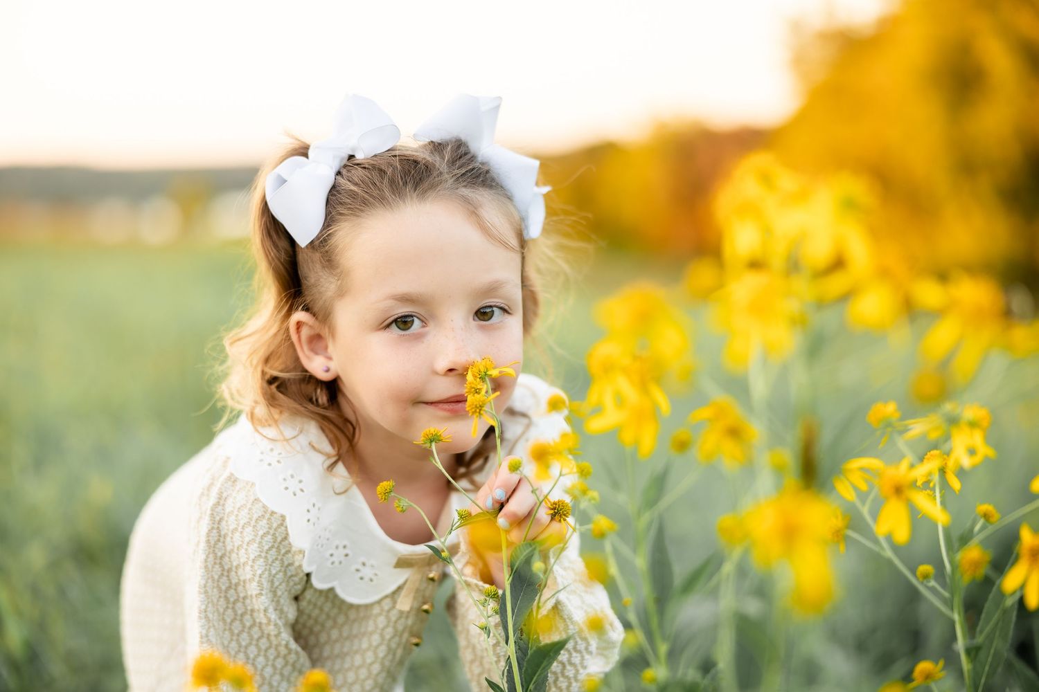 Child enjoying springtime in a field of bright yellow flowers and white daisies on a sunny afternoon.