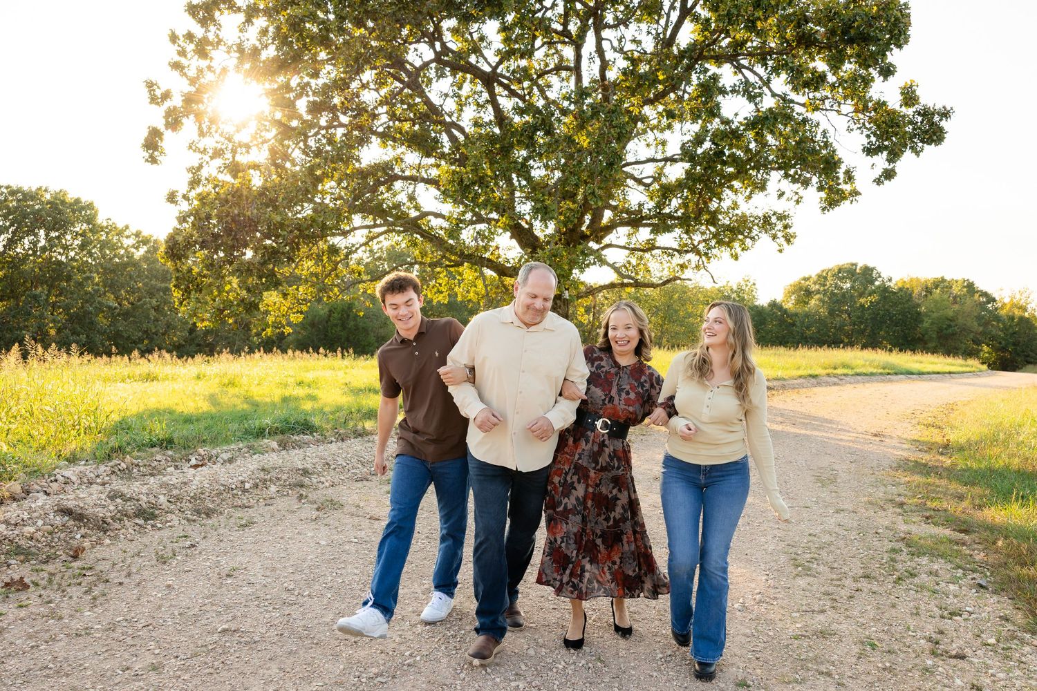 A group walking together through a sunlit field during golden hour at sunset.