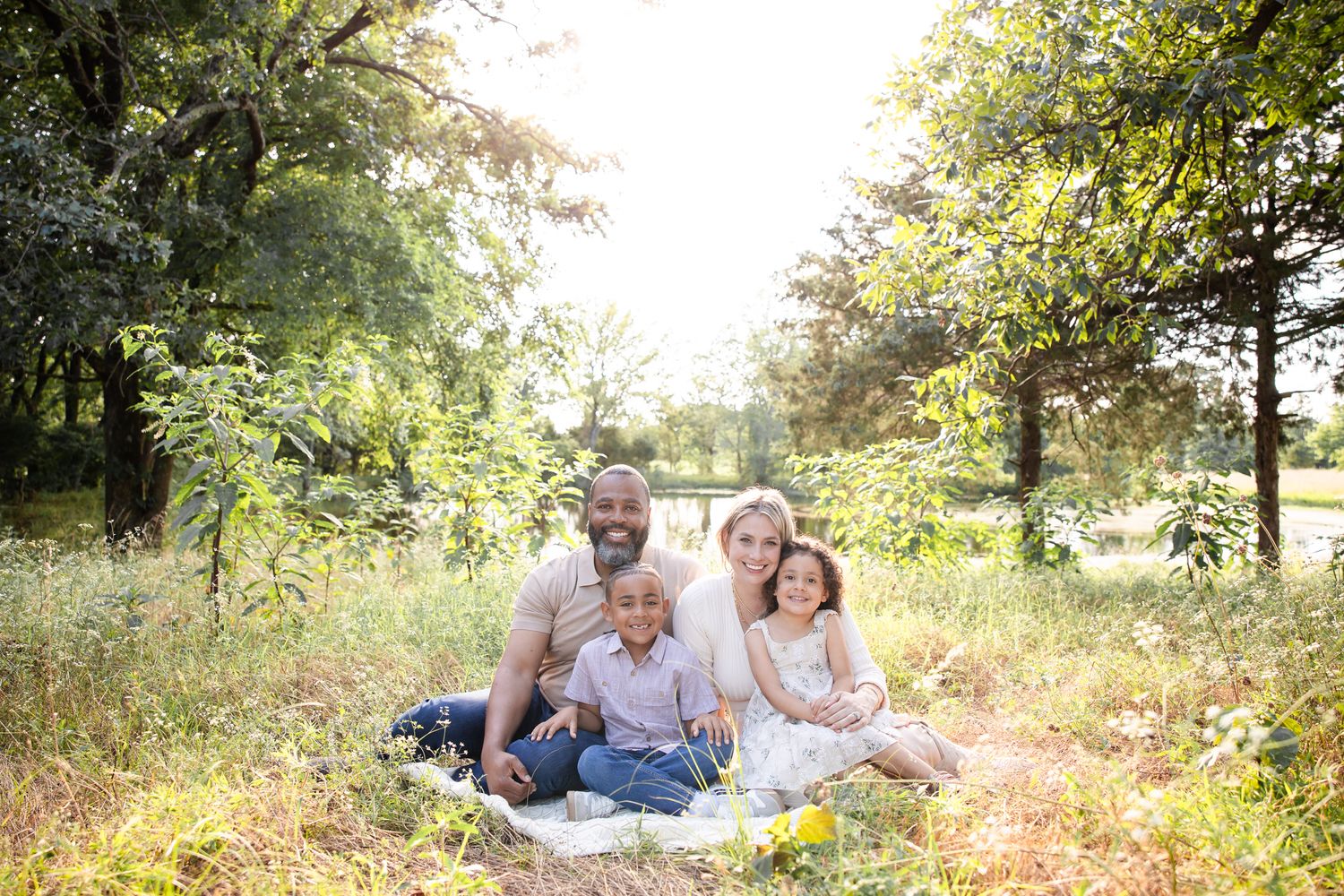 A group relaxes on a blanket in a sun-drenched meadow during a golden hour photo session.