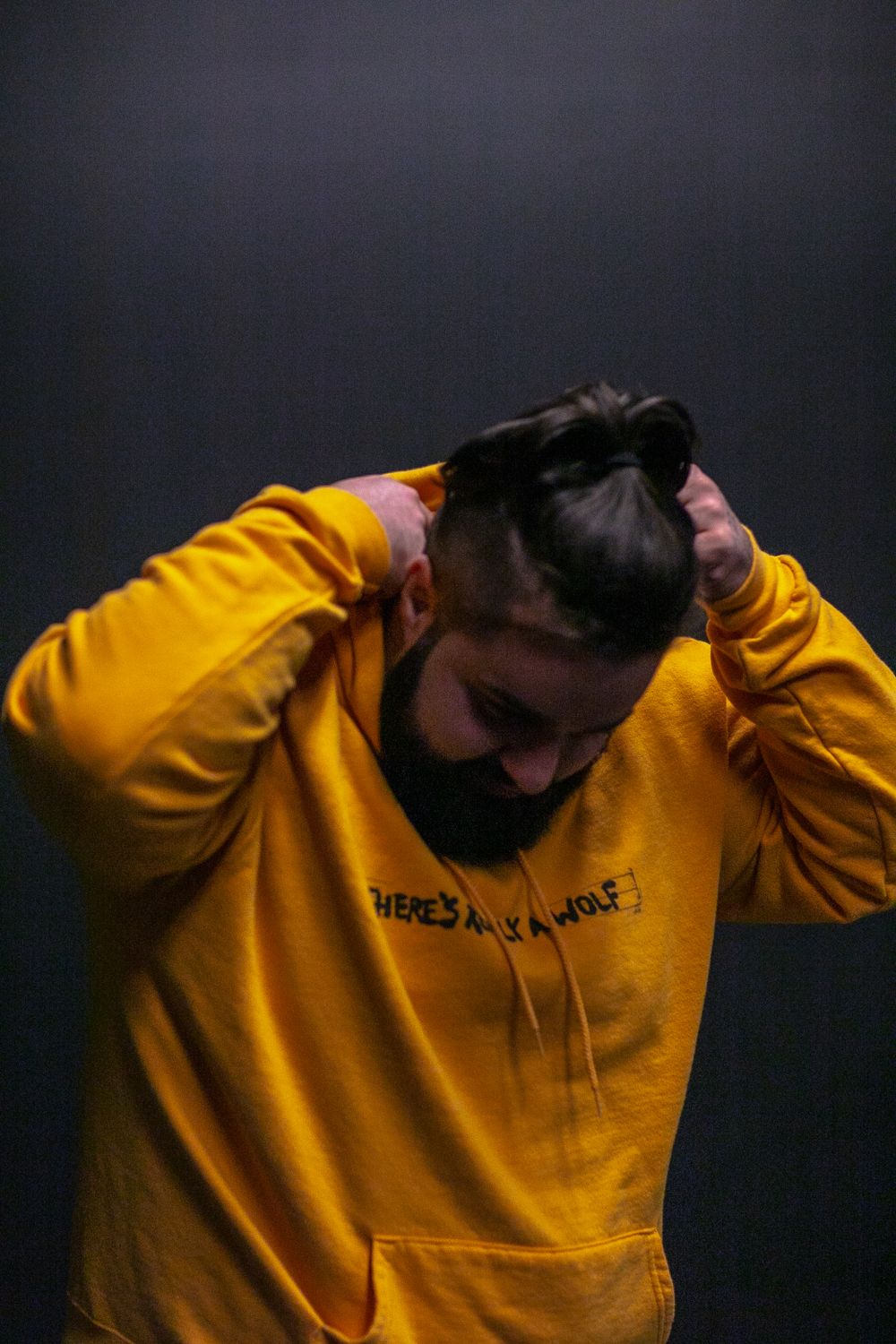 Person wearing bright yellow hoodie shown from side angles against dark background.