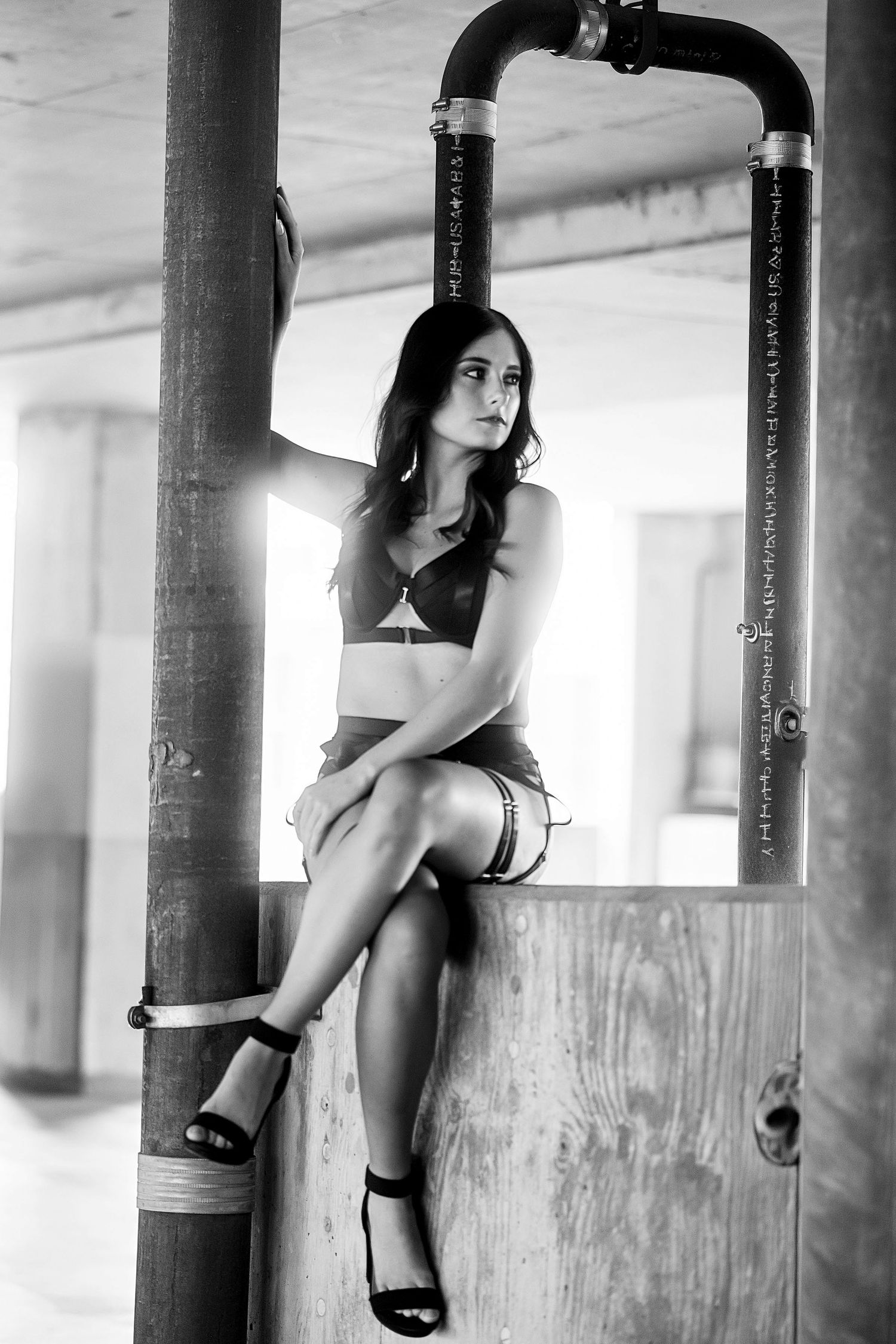 Young woman with dark hair posing in black lingerie against a teal wall in a studio boudoir photo.