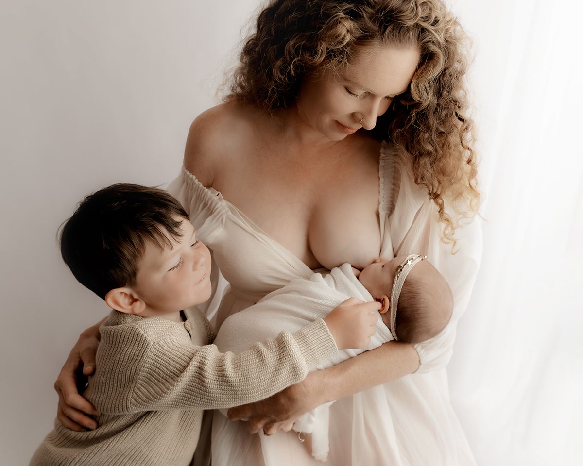 Mother holding and feeding newborn baby during photography session
