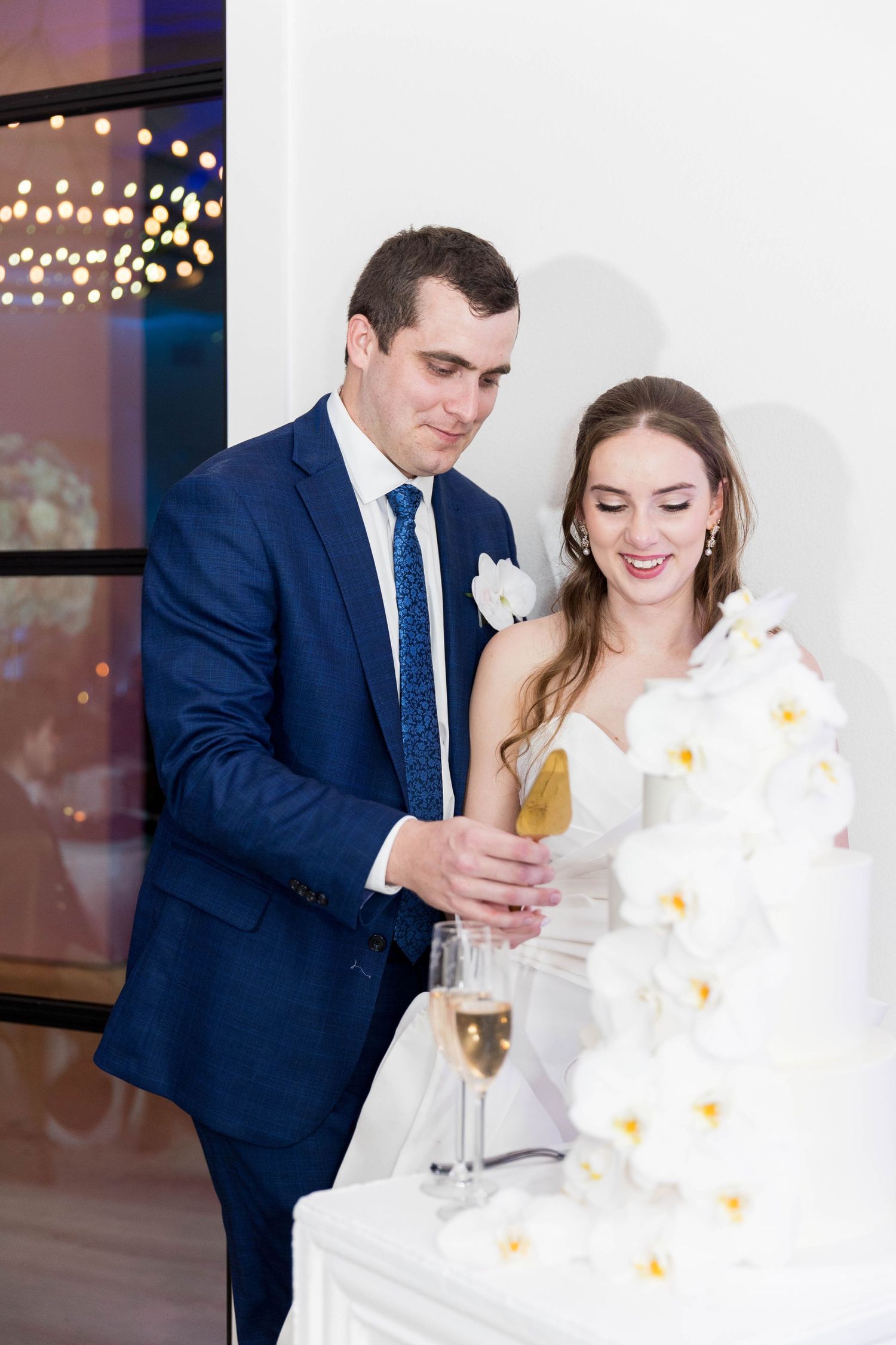 Bride in white strapless gown holding a baby in a polka dot jacket at a wedding reception.