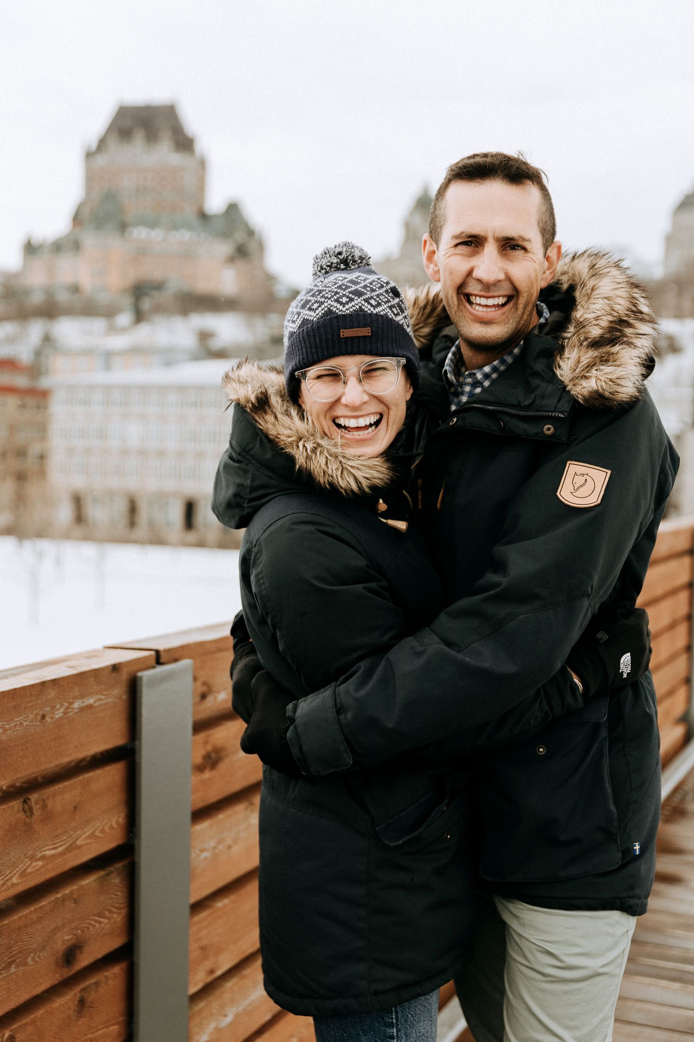 Couple enjoying winter views from observation deck with Chateau Frontenac in background.