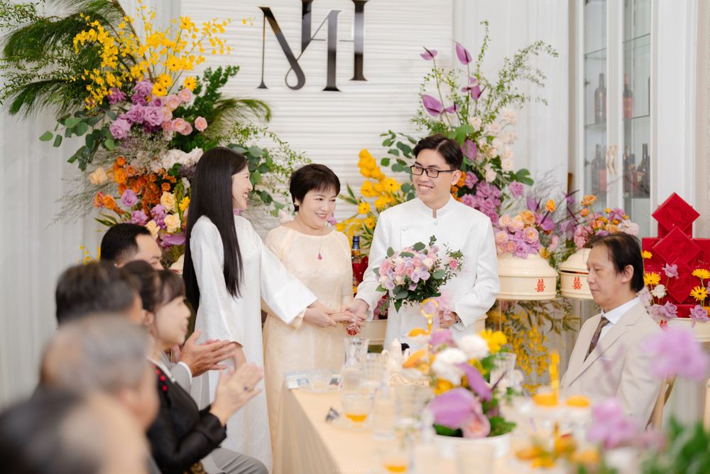 Vietnamese couple exchanges vows at elegant wedding ceremony with colorful floral arrangements.