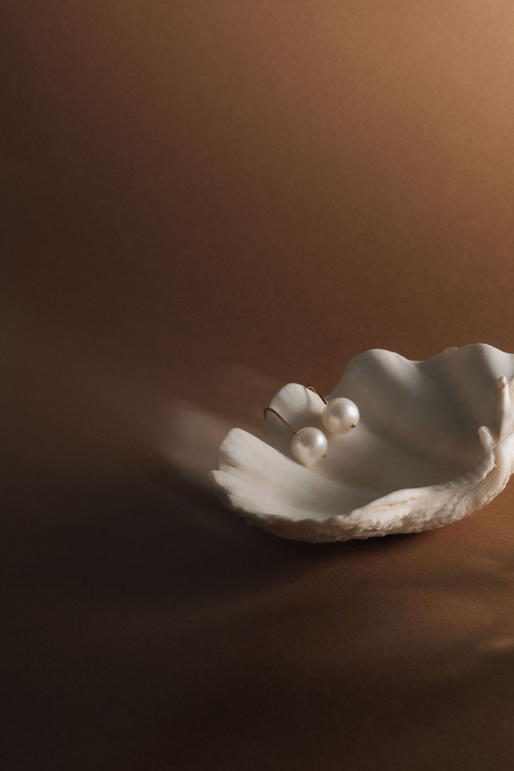 Artistic series of white feathers floating against a dark brown background creating an ethereal mood.